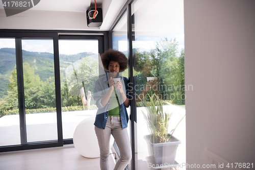 Image of African American woman drinking coffee looking out the window