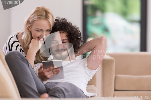 Image of couple relaxing at  home with tablet computers