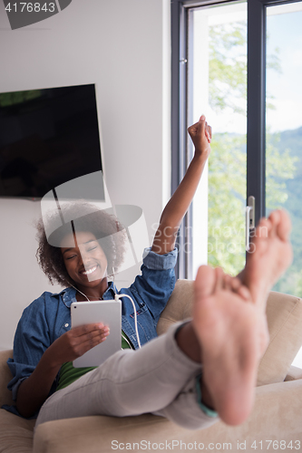 Image of African american woman at home in chair with tablet and head pho