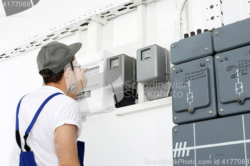 Image of Electrician repairs dashboard. Electrical repair, switching current. An electrician checks the status of the counter.