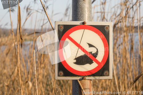 Image of No fishing sign on a post by a river