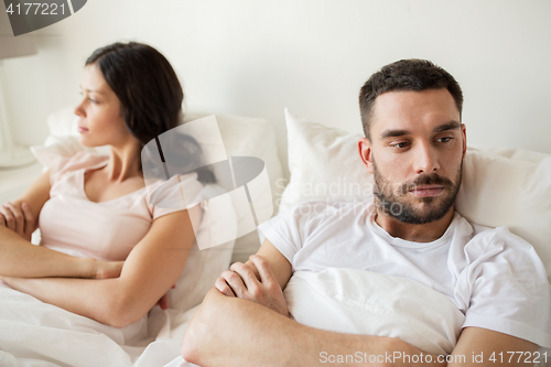 Image of unhappy couple having conflict in bed at home