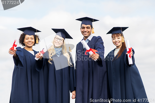 Image of happy students in mortar boards with diplomas