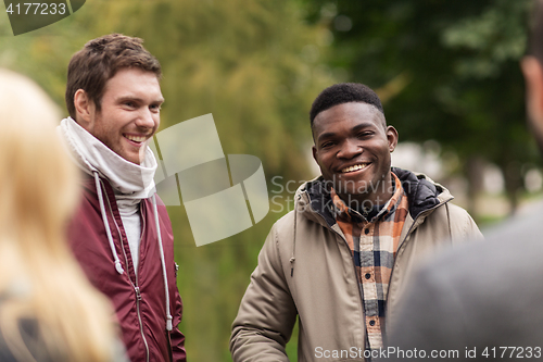 Image of happy friends walking along autumn park