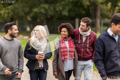 Image of happy friends walking along autumn park