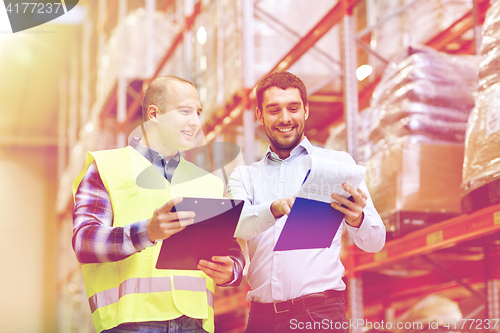 Image of worker and businessmen with clipboard at warehouse