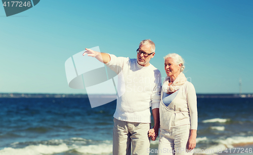Image of happy senior couple walking on summer beach