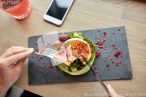 Image of woman eating goat cheese salad at restaurant