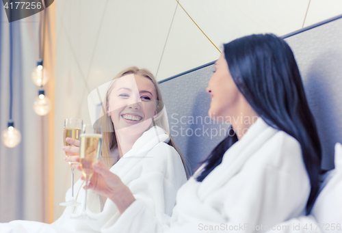 Image of smiling girlfriends with champagne glasses in bed