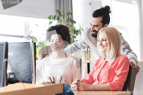 Image of happy creative team with computer in office