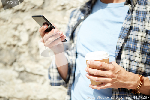 Image of man with smartphone and coffee on city street