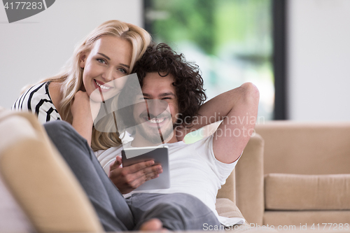 Image of couple relaxing at  home with tablet computers