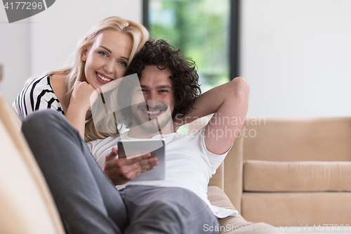 Image of couple relaxing at  home with tablet computers