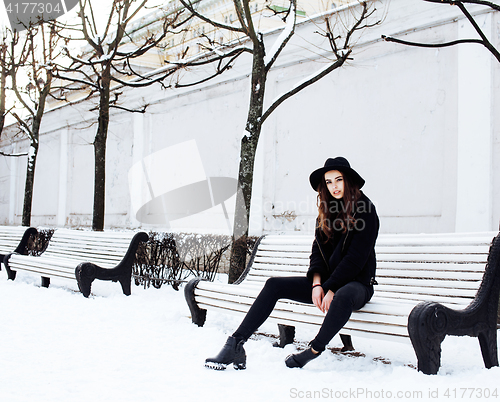 Image of young pretty modern hipster girl waiting on bench at winter snow park alone, lifestyle people concept 