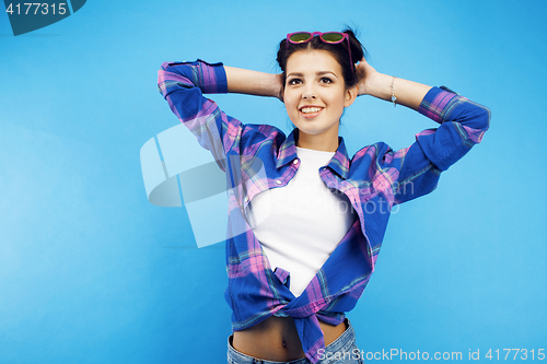 Image of young pretty teenage hipster girl posing emotional happy smiling on blue background, lifestyle people concept close up
