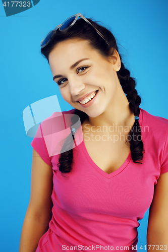 Image of young pretty teenage hipster girl posing emotional happy smiling on blue background, lifestyle people concept close up