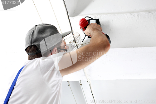 Image of Electrician repairs installations holding screwdriver and gauge.