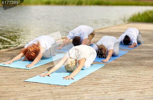 Image of group of people making yoga exercises outdoors