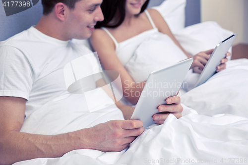 Image of smiling couple in bed with tablet pc computers