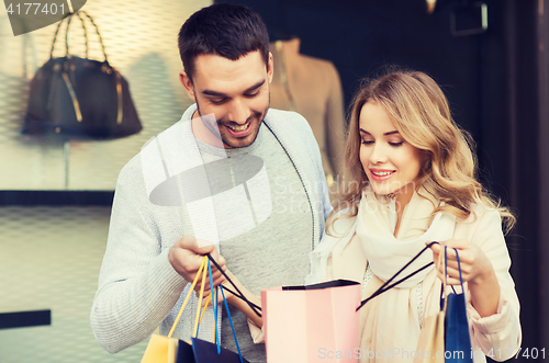 Image of happy couple with shopping bags at shop window