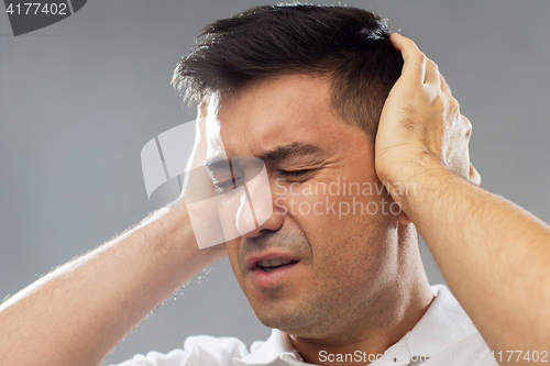 Image of close up of man suffering from noise closing ears