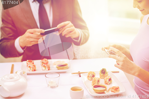 Image of close up of couple with smartphones at restaurant