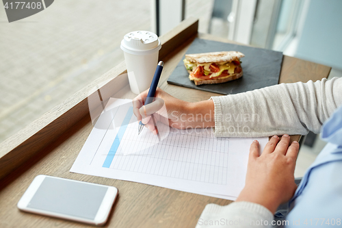 Image of woman with paper form having lunch at cafe