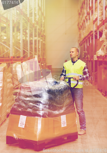 Image of man carrying loader with goods at warehouse