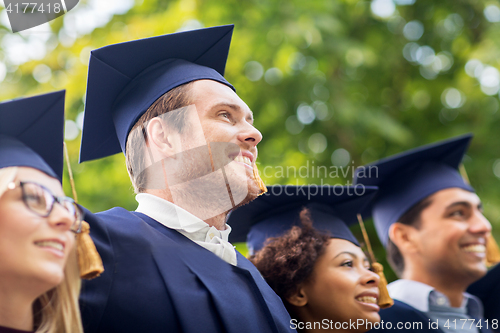 Image of happy students or bachelors in mortar boards