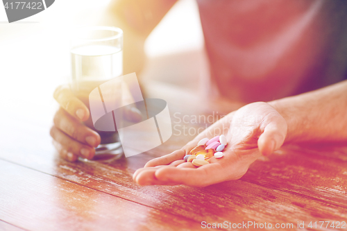 Image of close up of male hands holding pills and water