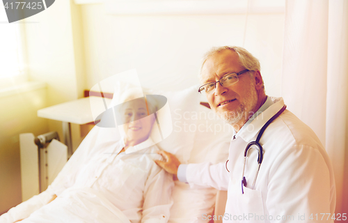 Image of doctor visiting senior woman at hospital ward