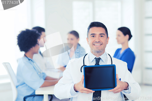 Image of happy doctor with tablet pc over team at clinic