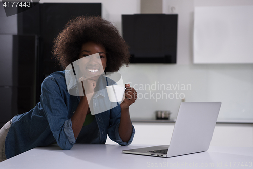 Image of smiling black woman in modern kitchen