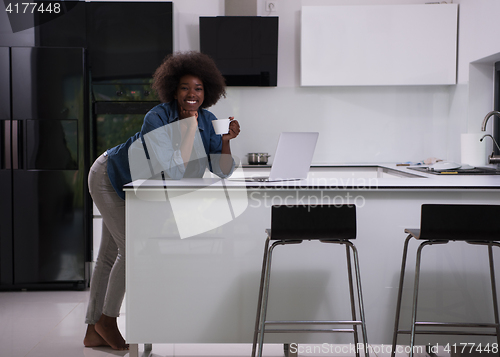 Image of smiling black woman in modern kitchen