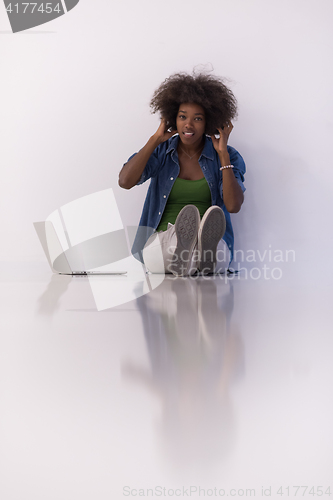 Image of african american woman sitting on floor with laptop