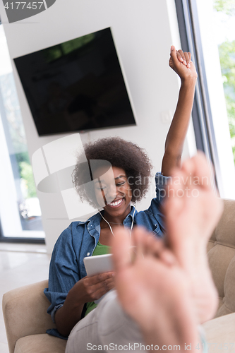 Image of African american woman at home in chair with tablet and head pho