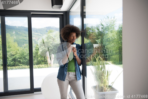 Image of African American woman drinking coffee looking out the window