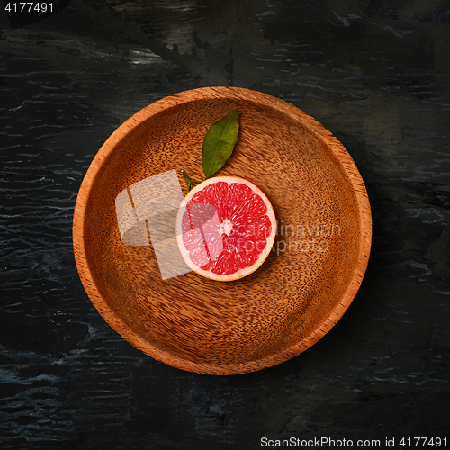 Image of Grapefruit citrus fruit halves on wooden plate