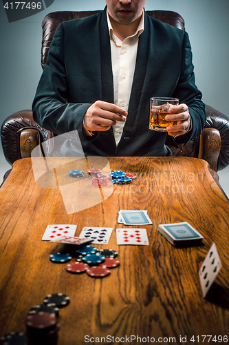 Image of The man, chips for gamblings, drink and playing cards