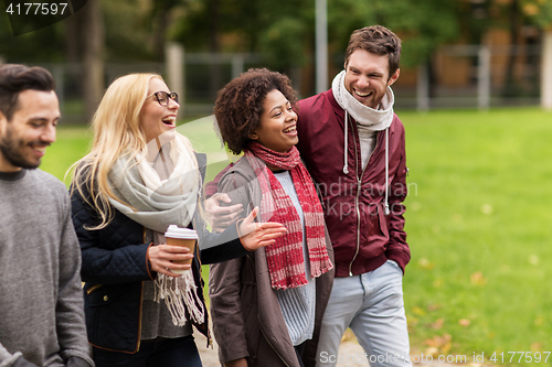 Image of happy friends walking along autumn park