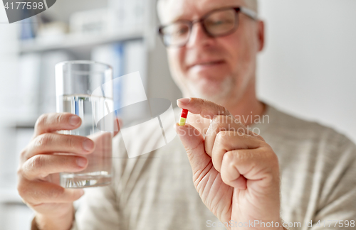 Image of close up of old man hands with pill and water