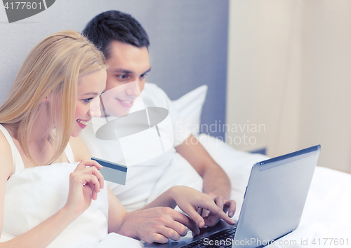 Image of couple in bed with laptop computer and credit card