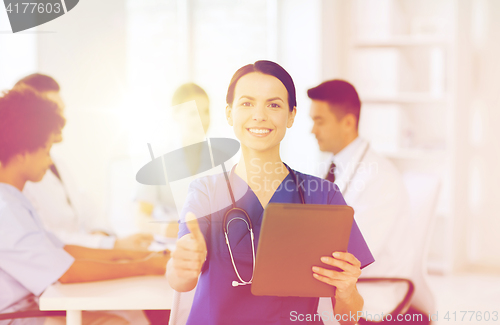 Image of happy doctor with tablet pc over team at clinic