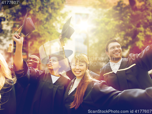 Image of happy students or bachelors waving mortar boards