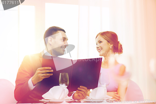 Image of smiling couple with menu at restaurant