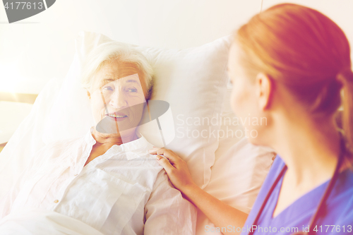 Image of doctor or nurse visiting senior woman at hospital