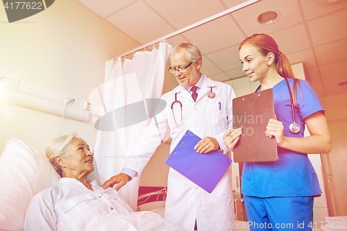 Image of doctor and nurse visiting senior woman at hospital