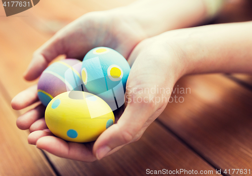 Image of close up of woman hands with colored easter eggs