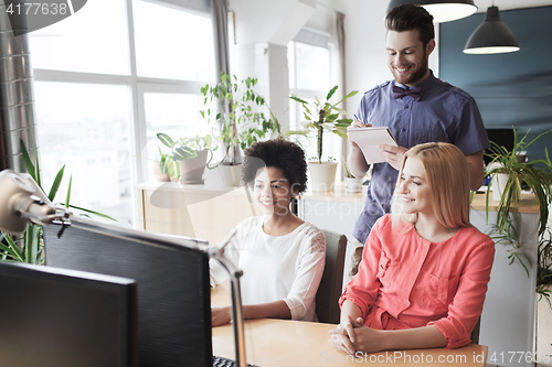 Image of happy creative team with computer in office