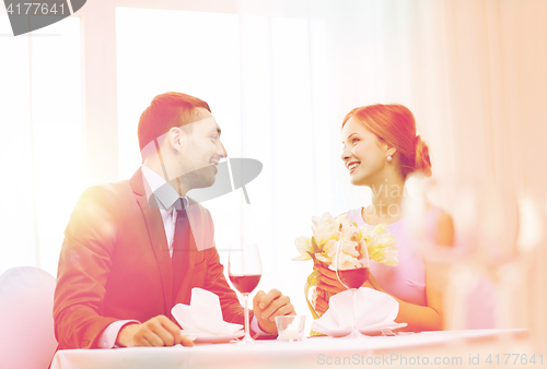 Image of smiling man giving flower bouquet at restaurant